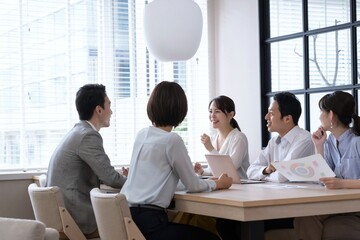 女性と男性が笑顔で会議をしている写真