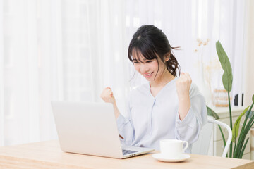 パソコンを見ながら喜んでいる女性の写真